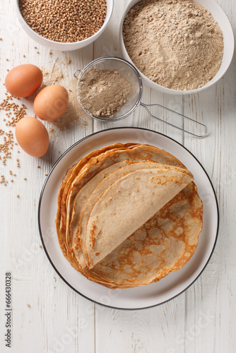 Quadro em tela Traditional French Savory Buckwheat Galettes Bretonnes pancakes on a table with flour, cereal and eggs closeup on the white wooden table