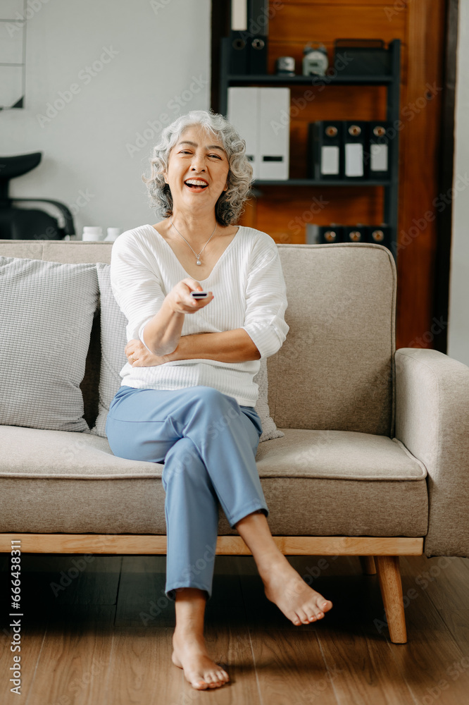 Asian old woman is watching tv and sitting on the sofa in living room Asian old woman is watching tv and sitting on the sofa in living room