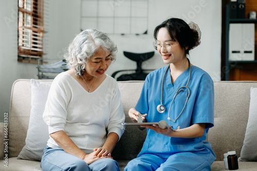 Asian caregiver doctor examine older patient use blood pressure gauge. woman therapist nurse at nursing home taking care of senior elderly woman sit on sofa.Medical service concept.