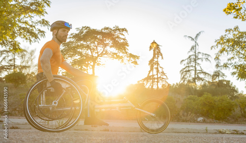 Athlete sitting in wheelchair on road at sunset photo