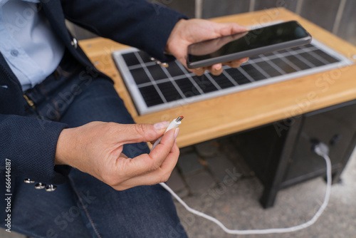 Businesswoman plugging USB cable in smart phone at solar charging point photo