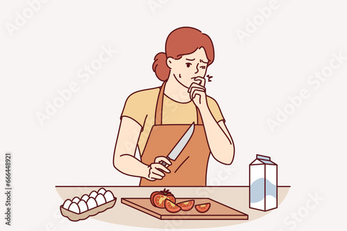 Woman housewife cooking dinner cut finger and trying to stop bleeding, standing in kitchen near table with cutting board. Woman cook preparing salad for dinner got hurt and needs plaster or bandages