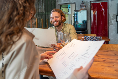 Smiling man holding menu card with woman sitting in cafe