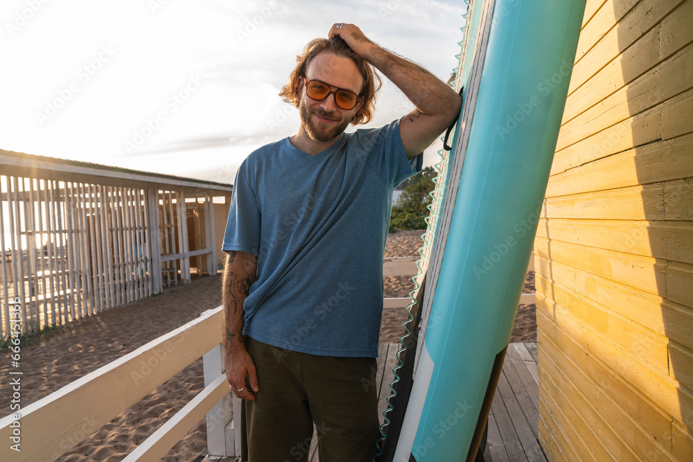 Smiling man with hand in hair standing near beach hut Smiling man with hand in hair standing near beach hut