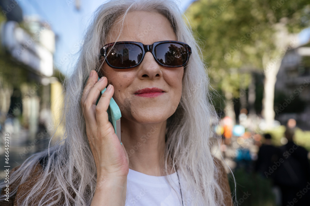 Smiling businesswoman wearing sunglasses talking on mobile phone Smiling businesswoman wearing sunglasses talking on mobile phone