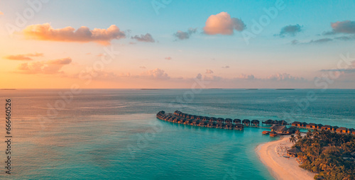 Aerial sunset panoramic landscape luxury tropical resort water villas. Beautiful island beach orange sunrise sea sky. Amazing bird eyes panorama Maldives paradise tropical bay. Exotic summer vacation 