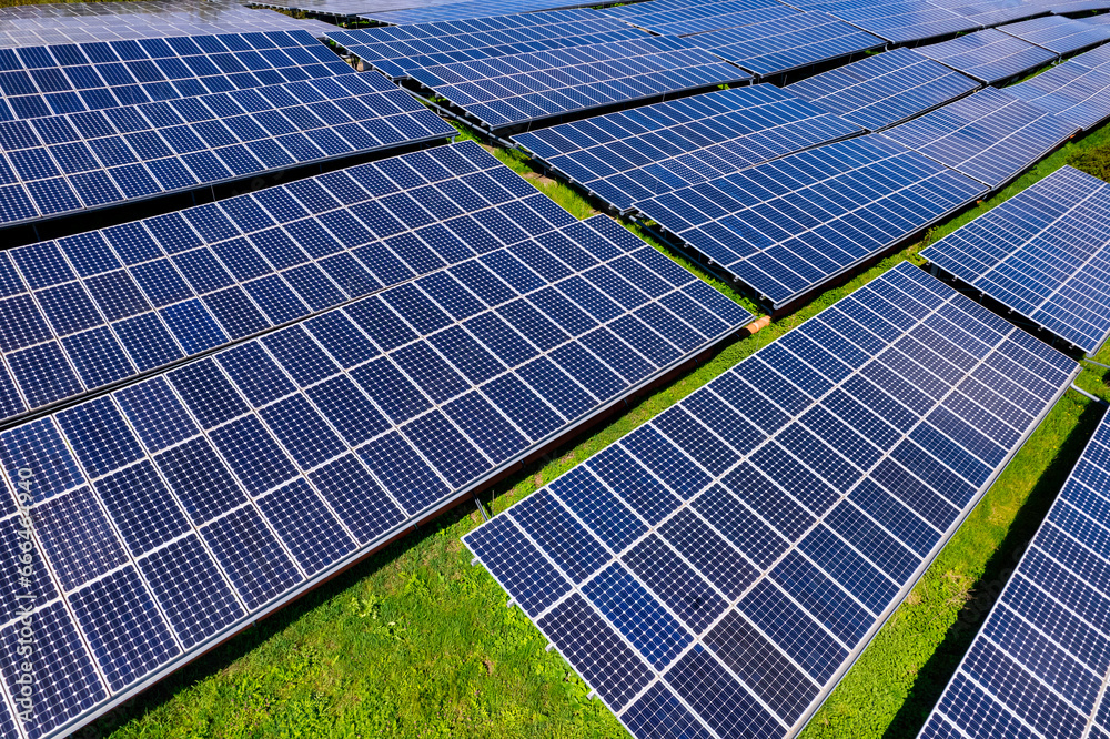 Flying over a solar farm with photovoltaic panels converting solar power to electricity for green energy on agricultural land