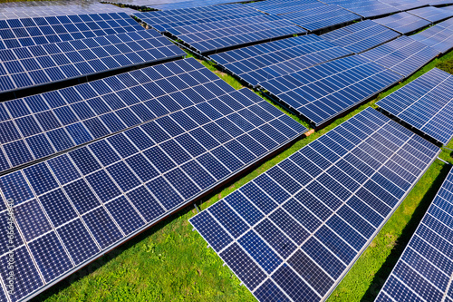 Obraz na płótnie Flying over a solar farm with photovoltaic panels converting solar power to electricity for green energy on agricultural land w salonie