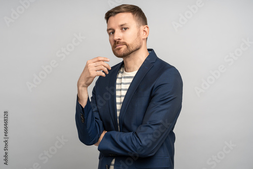 Charismatic serious relaxed unshaved man isolated on grey studio background with hands crossed on chest. Stylish man looks like manager, businessman, entrepreneur, freelancer, employee, executive