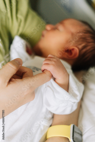 Detail of a newborn hand holding his fathers finger