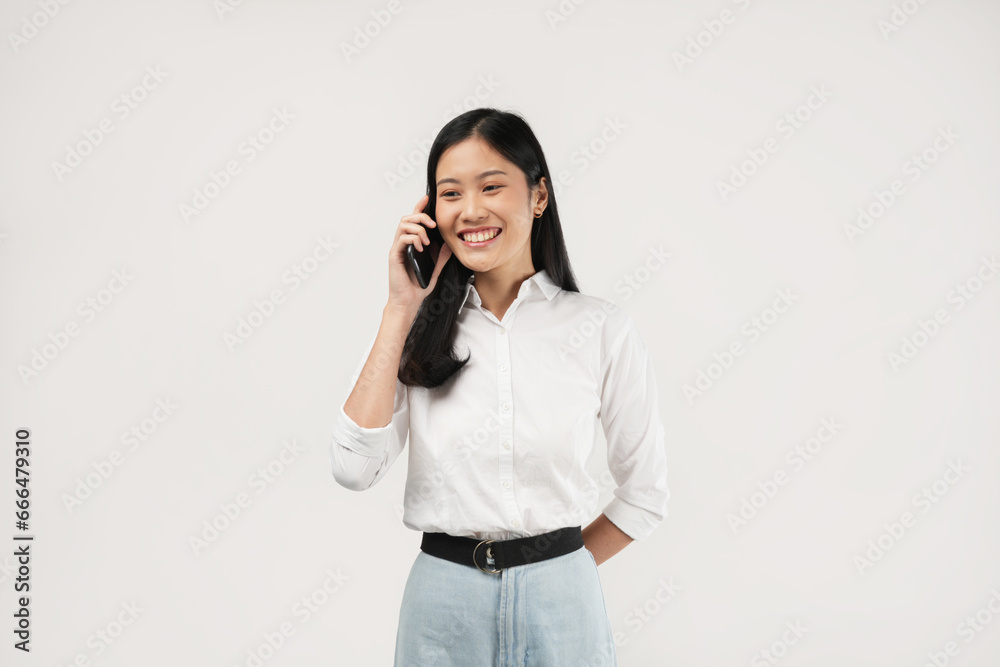 Portrait of a young Asian woman smiling while talking the phone, isolated on a white background. Portrait of a young Asian woman smiling while talking the phone, isolated on a white background.