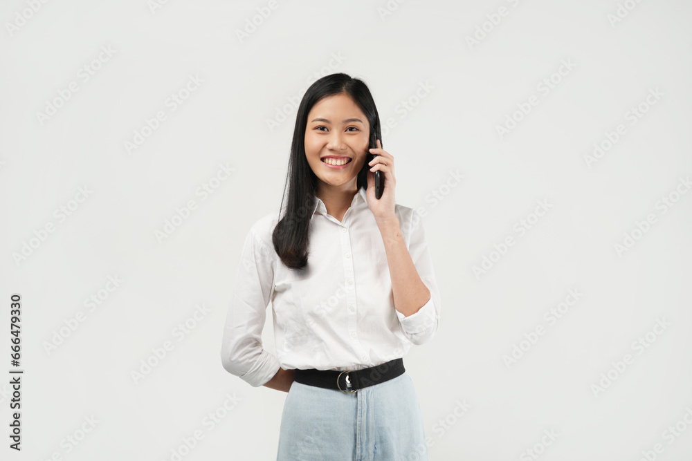 Portrait of a young Asian woman smiling while talking the phone, isolated on a white background. Portrait of a young Asian woman smiling while talking the phone, isolated on a white background.