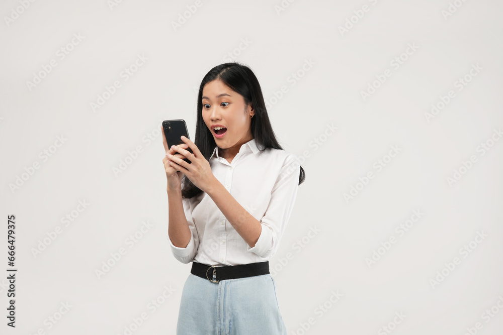 Portrait of a young Asian woman of shocked screaming holding phone in hand isolated on white background. Portrait of a young Asian woman of shocked screaming holding phone in hand isolated on white background.
