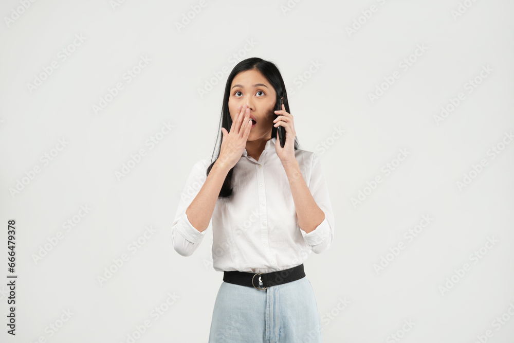 Portrait of a young Asian woman of shocked screaming holding phone in hand isolated on white background. Portrait of a young Asian woman of shocked screaming holding phone in hand isolated on white background.