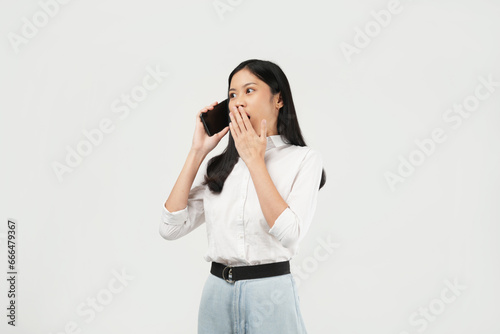 Portrait of a young Asian woman of shocked screaming holding phone in hand isolated on white background.