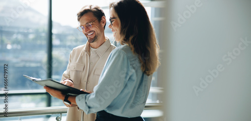Two business people smiling as they go through a document together in an office photo