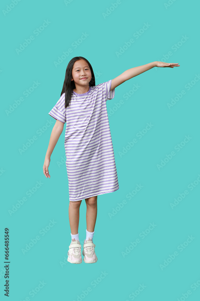 Asian young girl raised her hand to measure something isolated on green background. Image full length with Clipping path. Asian young girl raised her hand to measure something isolated on green background. Image full length with Clipping path.
