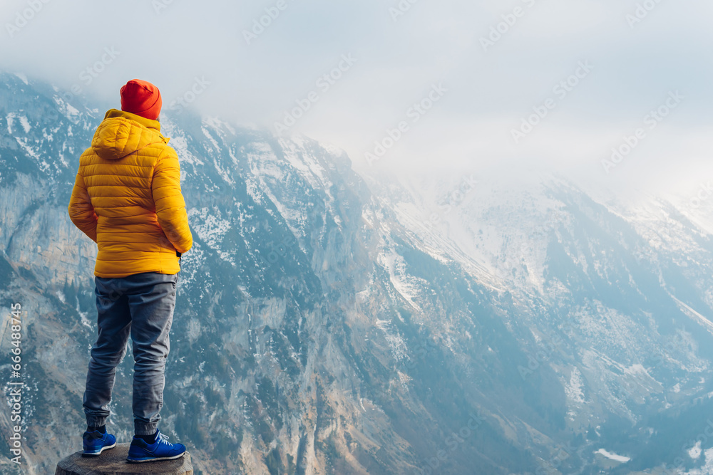 Rear view of a man in warm clothes on the snowy mountain. adventure travel and equipment.