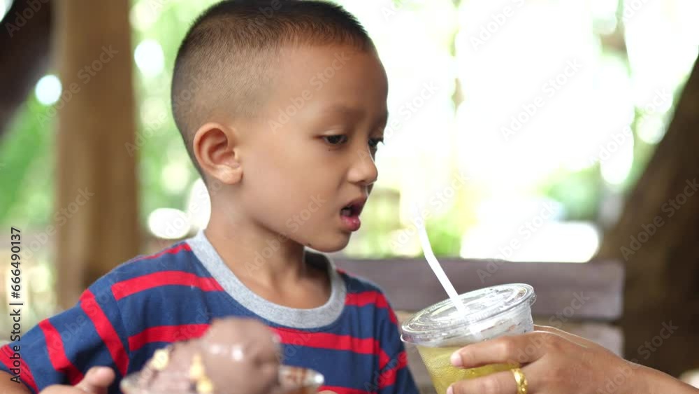 A woman gives fruit juice to her son to drink. A woman gives fruit juice to her son to drink.