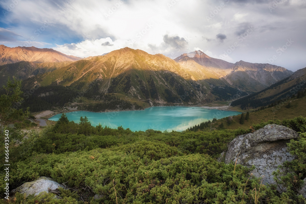 Big Almaty Lake in the mountains of Kazakhstan with the participation of juniper bushes