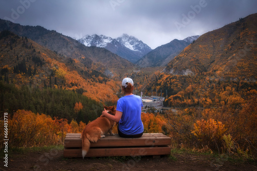 Obraz na płótnie A woman with a dog admires the mountain autumn landscape of the Medeo gorge in the city of Almaty in Kazakhstan