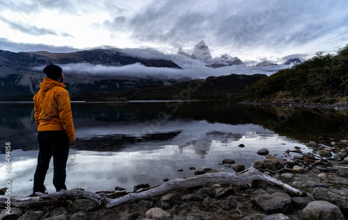 A person standing on a rock in front of a lake