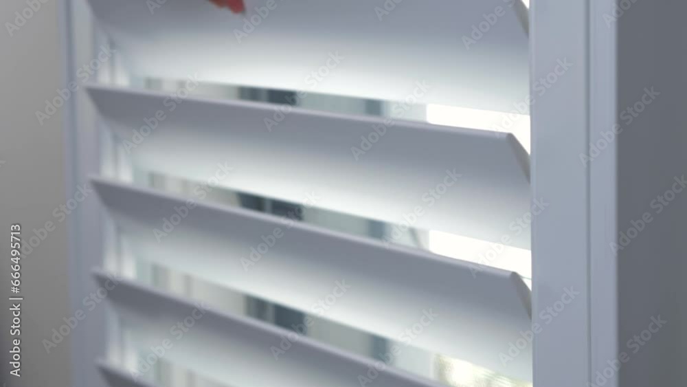 Close-up shot of Plantation Shutters window frame slats being closed with hands in house interior design wall kitchen privacy security protection 4K