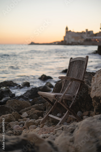 Silla en las rocas con Catedral de Sitges de fondo