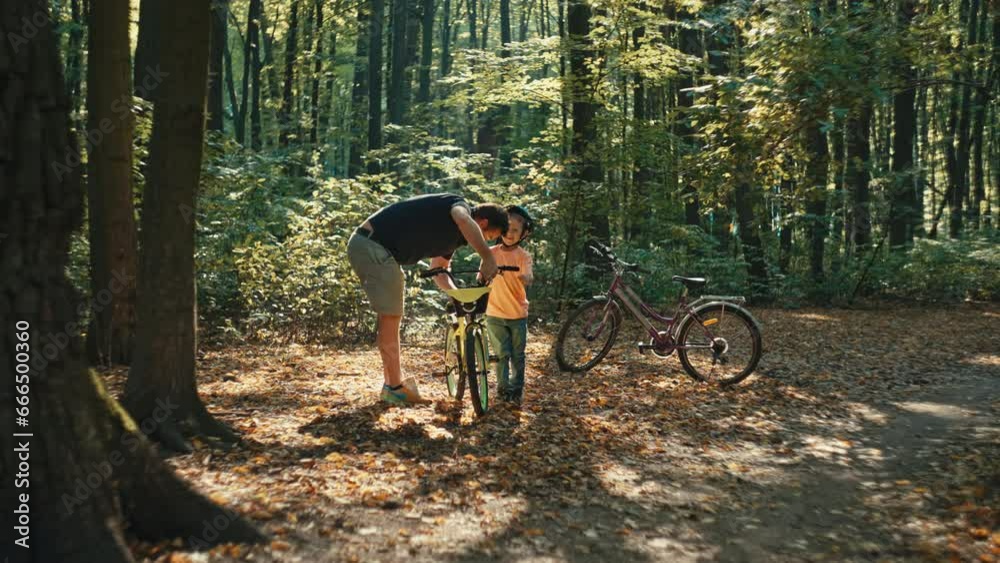 A father and son are repairing a bicycle in the forest. Time spent together with parents and children in nature on active recreation. A man teaches a boy to repair. High quality 4k footage A father and son are repairing a bicycle in the forest. Time spent together with parents and children in nature on active recreation. A man teaches a boy to repair. High quality 4k footage
