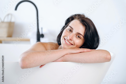 Portrait of cheerful smiling woman sitting in bathtub
