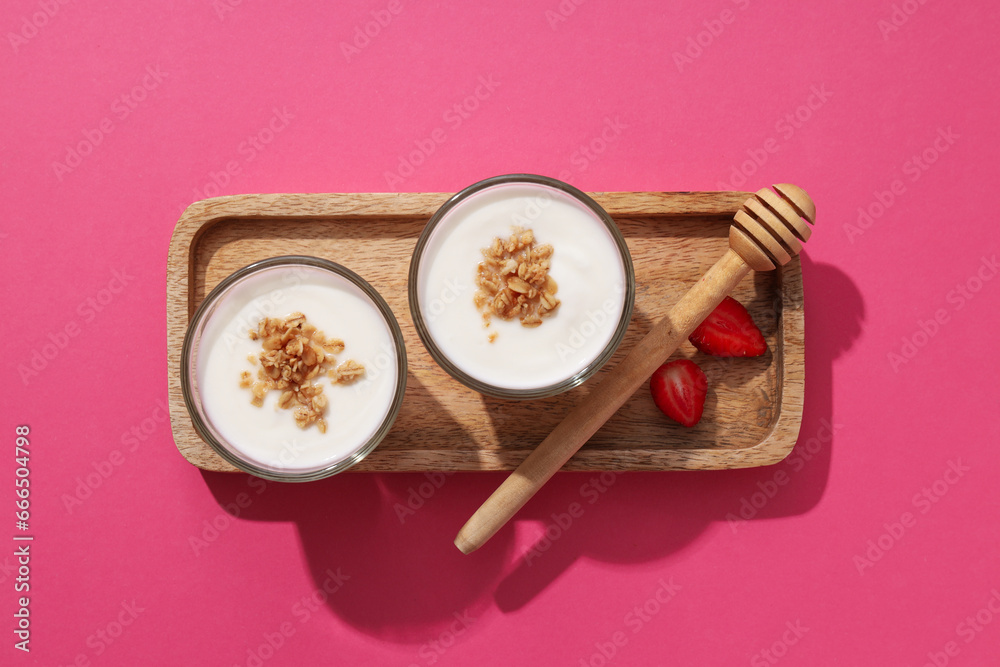 Bowls with yogurt on wooden stand on pink background, top view Bowls with yogurt on wooden stand on pink background, top view