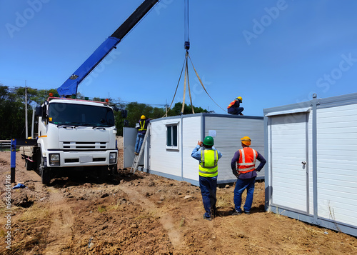 The Crane trucks transport the mobile office buildings or container site office for installation in the construction site area, project mobilization.