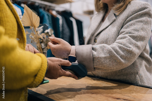 Close-up view of contactless transaction via smartwatch in boutique. photo