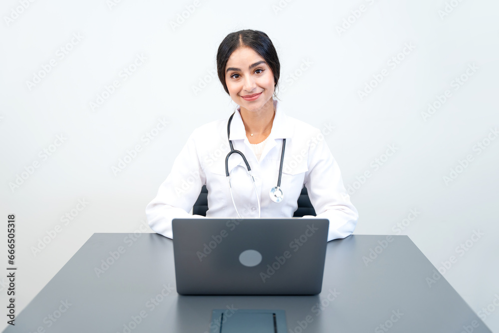 Pretty indian woman GP doctor in uniform sitting at the laptop. Online medicine, remote consultation and health care. Pretty indian woman GP doctor in uniform sitting at the laptop. Online medicine, remote consultation and health care.