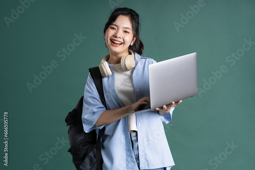 Portrait of a beautiful Asian student on a green background