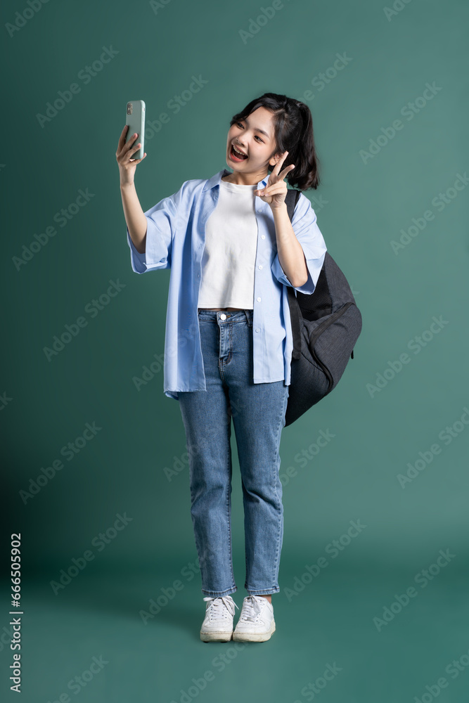 Portrait of a beautiful Asian student on a green background