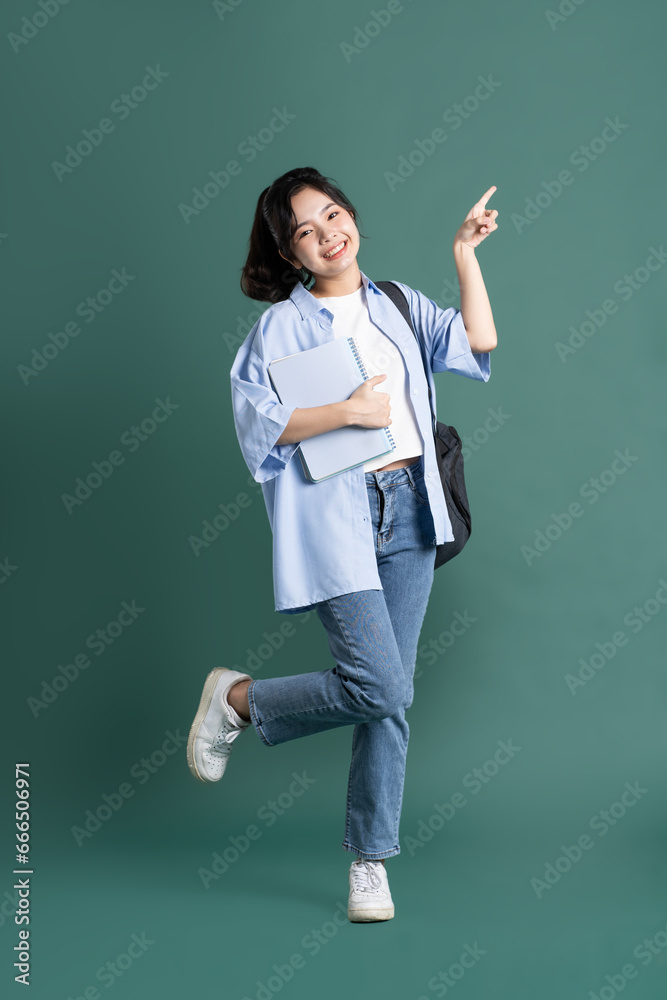 Portrait of a beautiful Asian student on a green background