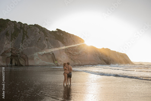 Pregnant couple kissing in sea in evening photo