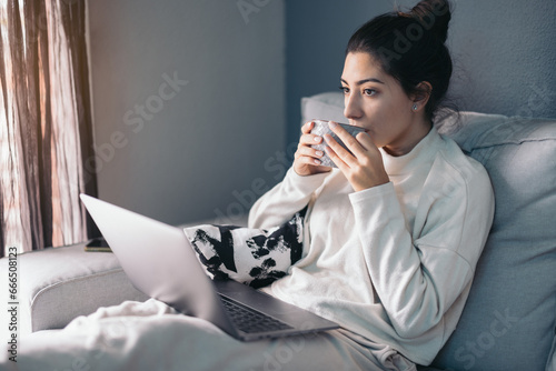 Crop young woman sitting with laptop and coffee cup photo