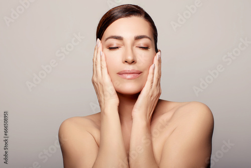 Beautiful woman with rejuvenated facial skin relaxing at spa. With copyspace.