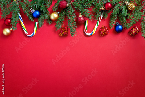 Holiday Christmas and New Year red background with candy canes, fir tree branches and xmas balls.