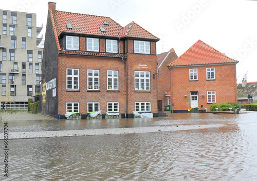 Flooded Danish city under a storm surge with muddy water flooding the streets and sand bags in front of the houses to prevent the water coming in