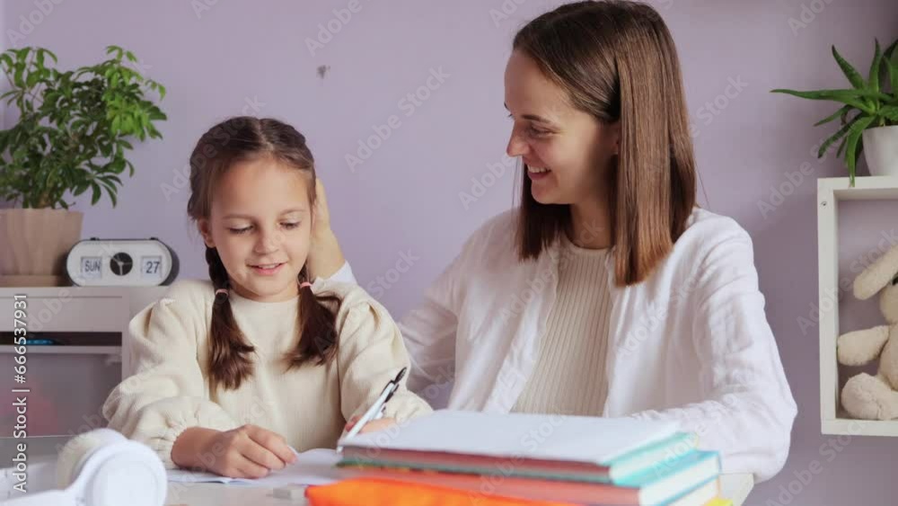 Enthusiastic young girl with pigtails happily engaged in her schoolwork with her mother's guidance within the cozy interior of their home tutor displaying content expression enjoys the lesson.