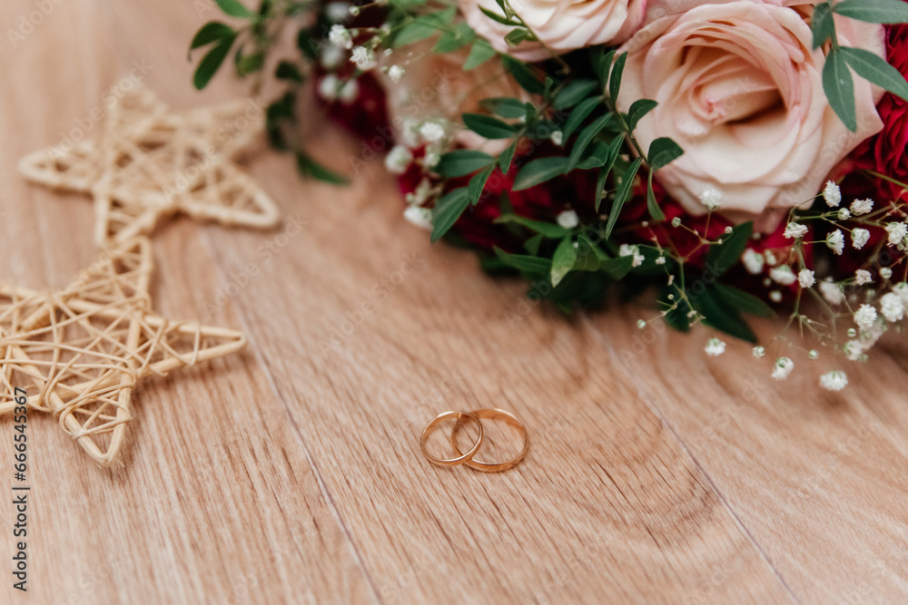 Gold wedding rings near the bride's bouquet of beige-red roses Gold wedding rings near the bride's bouquet of beige-red roses