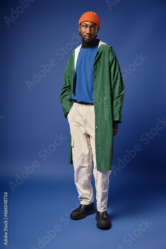 full length, african american model in knitted hat and winter attire posing with hand in pocket