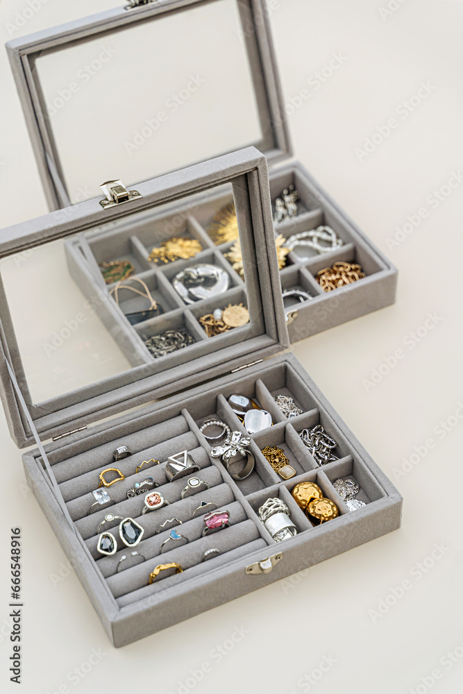 Jewelry box with trendy bijouterie. Stylish silver and golden  rings, chains, necklace, earrings and bracelets in jewelry case. Storage system for women's jewelry. Fashion accessories.