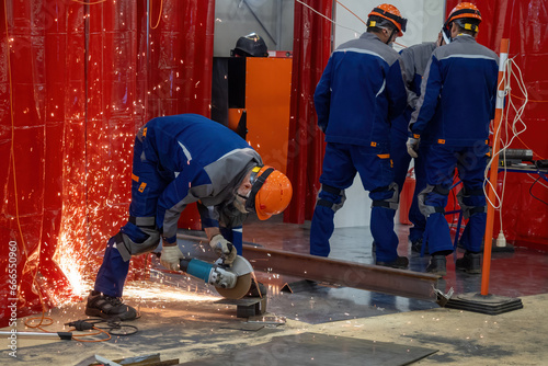 Construction works. Man with circular saw. Worker saws metal. Guy in helmet holds hand-held circular saw. Construction worker uses mask to protect against sparks. Circular saw rental concept