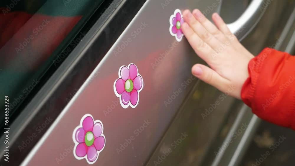 little girl puts sticker in shape of flower on car