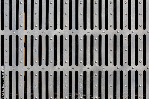 iron drainage grate with stripes  industrial object design  close-up surface texture.