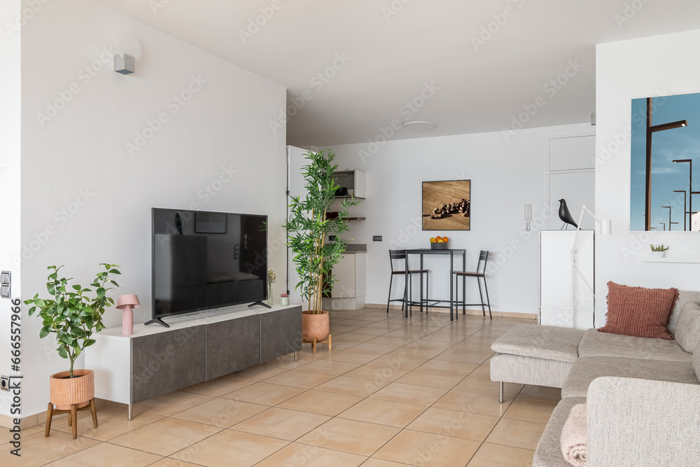 Fototapeta premium Plasma TV screen on podium and soft sofa in modern apartment
